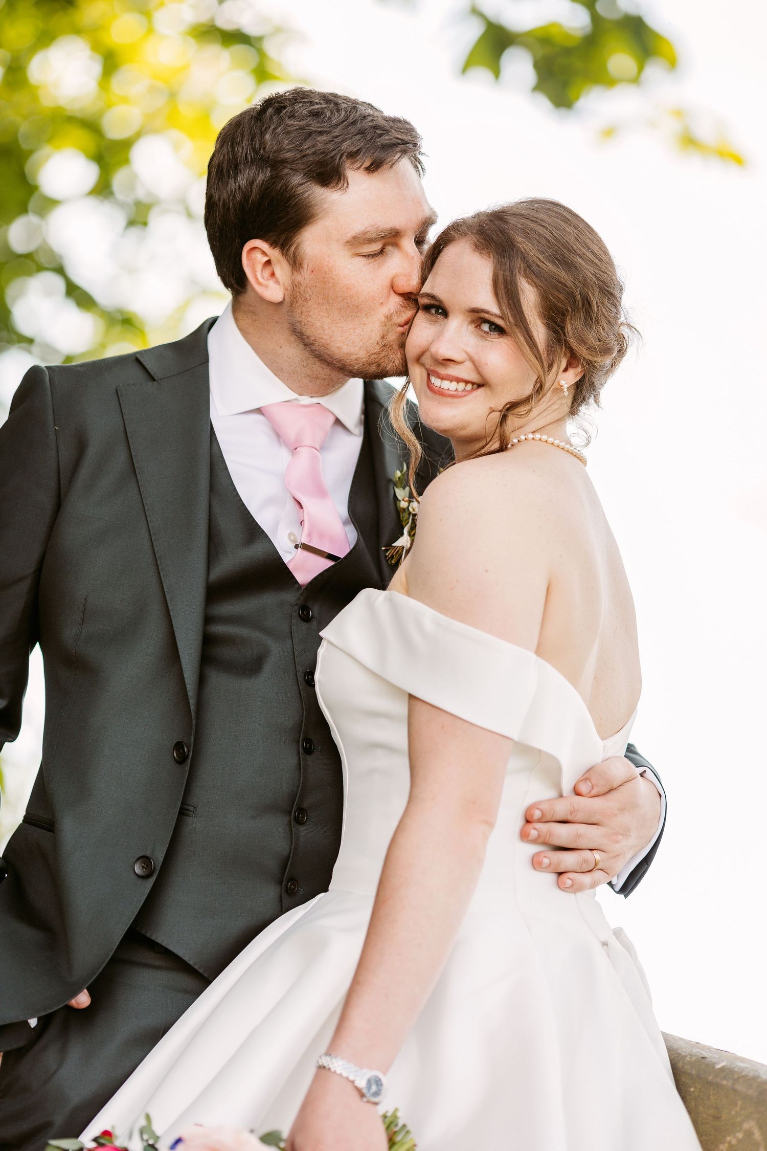 Groom kissing his beautiful bride on the cheek as she smiles happily Henley on Thames