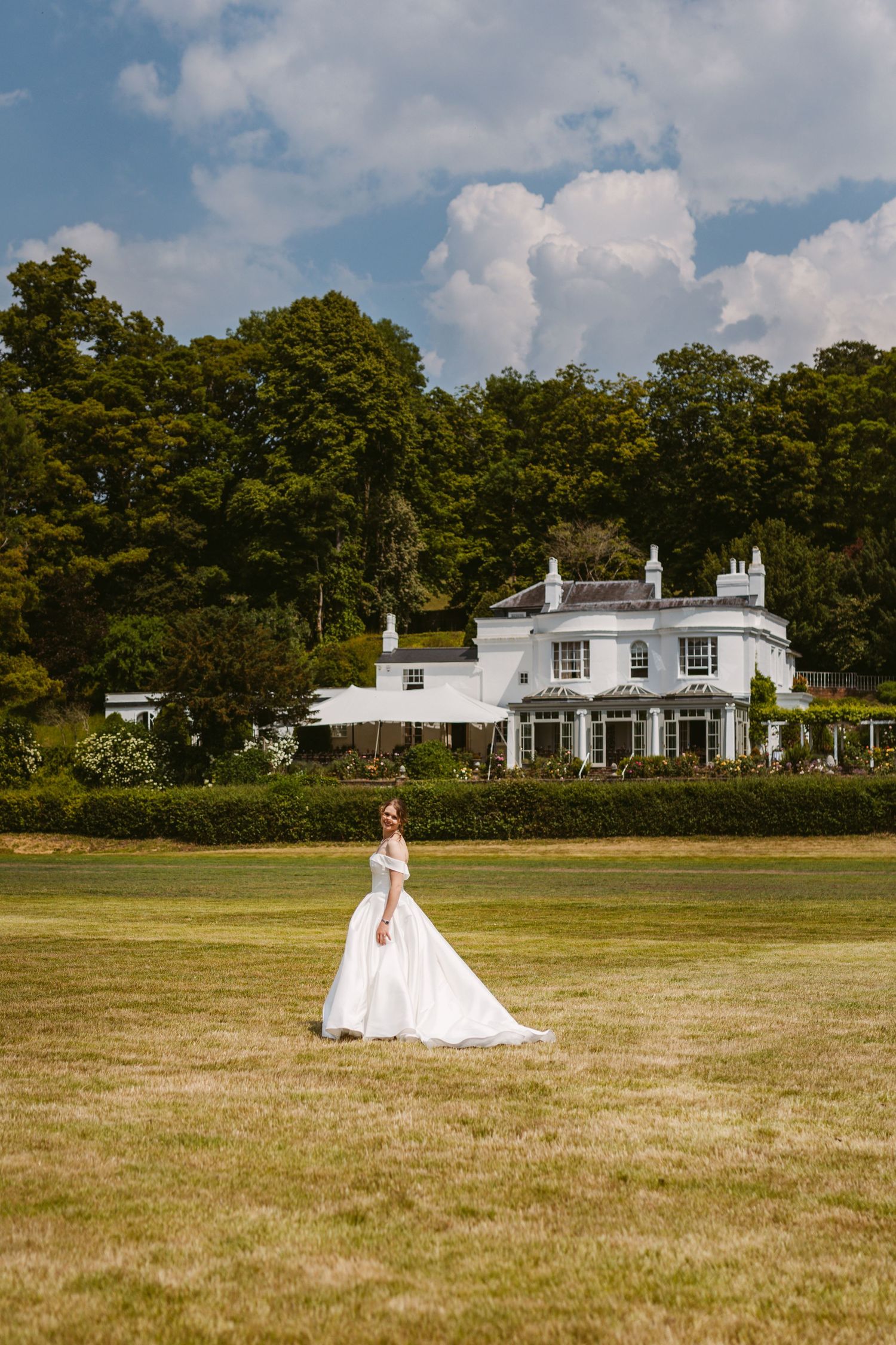 Beautiful bride walking across lawn swooshing dress at Remenham Court Henley on Thames