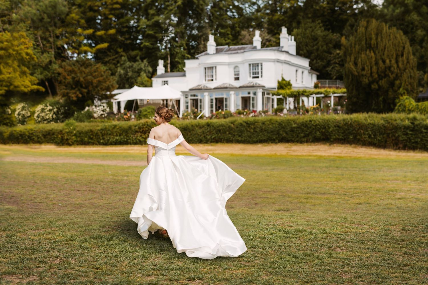 Beautiful bride running across lawn bride swooshing dress at Remenham Court Henley on Thames
