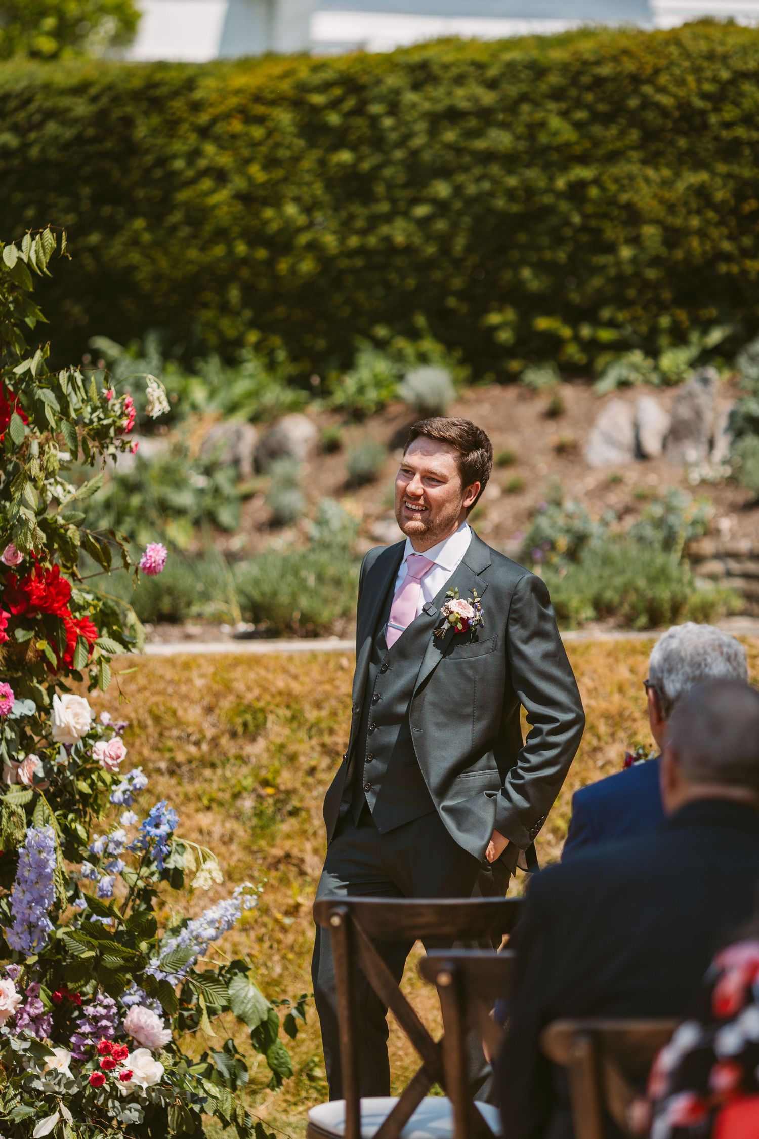 Smiling Groom in position at the top of the aisle outdoor ceremony waiting for bride to arrive