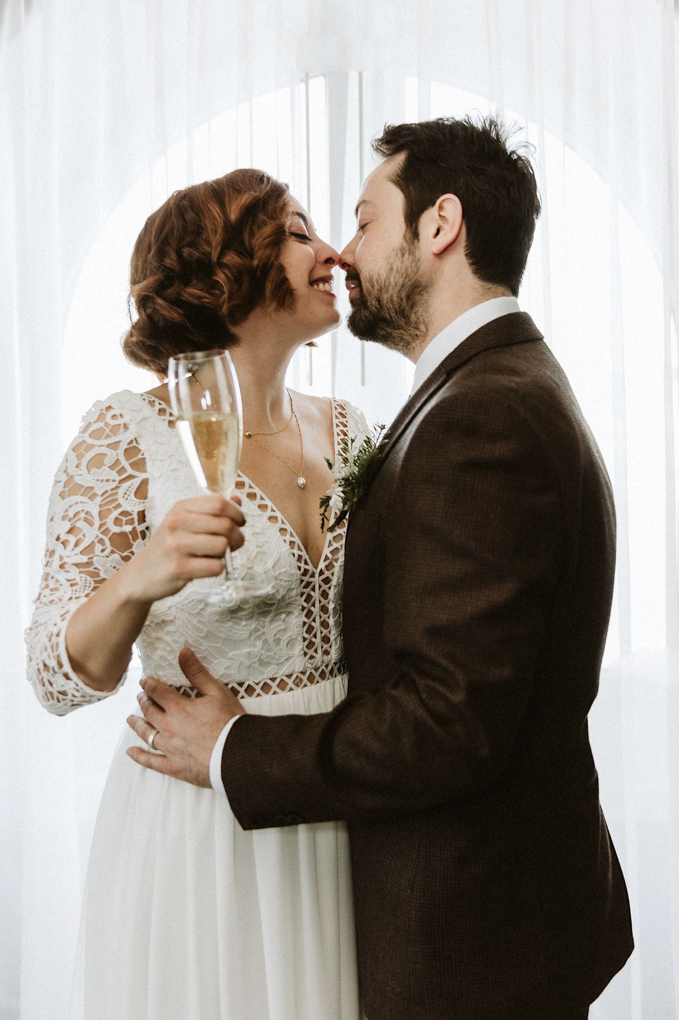 A romantic wedding toast moment with champagne glasses and delicate lace dress details.