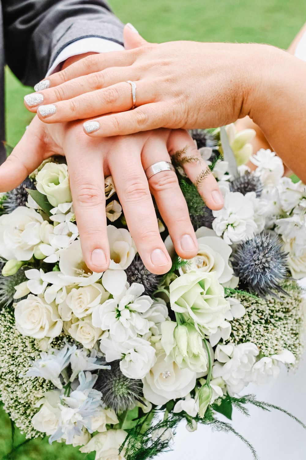 Hands delicately arranging white floral bouquet with hydrangeas and decorative accents.