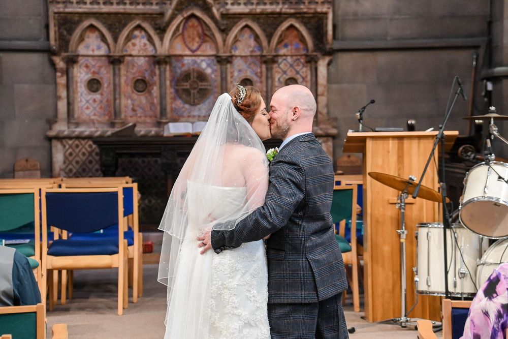 Wedding ceremony inside historic church with wooden details and warm lighting.
