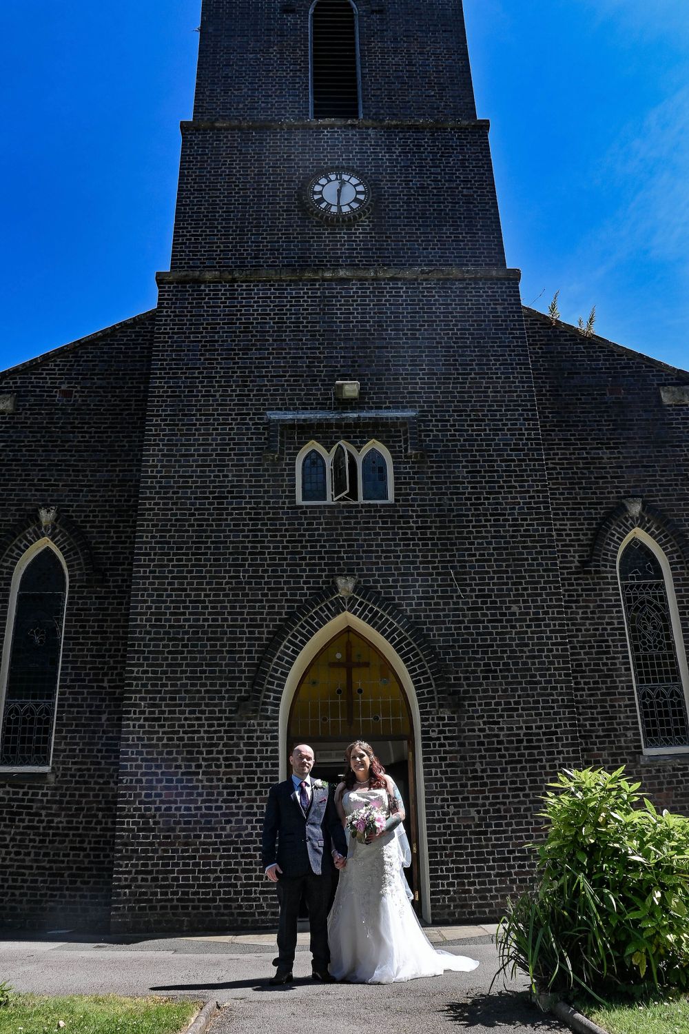 Exterior shots of gothic brick church building against bright blue sky.