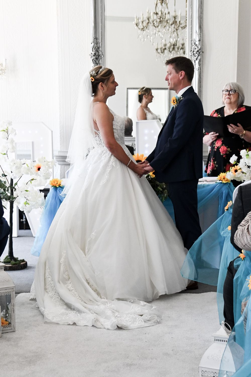 Reception moments in white room with chandelier and light blue decor accents.