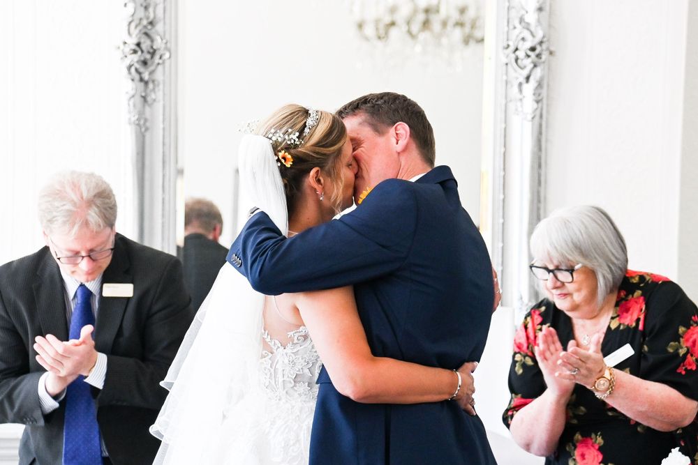 Intimate moments during wedding reception in elegant white room with crystal chandeliers.