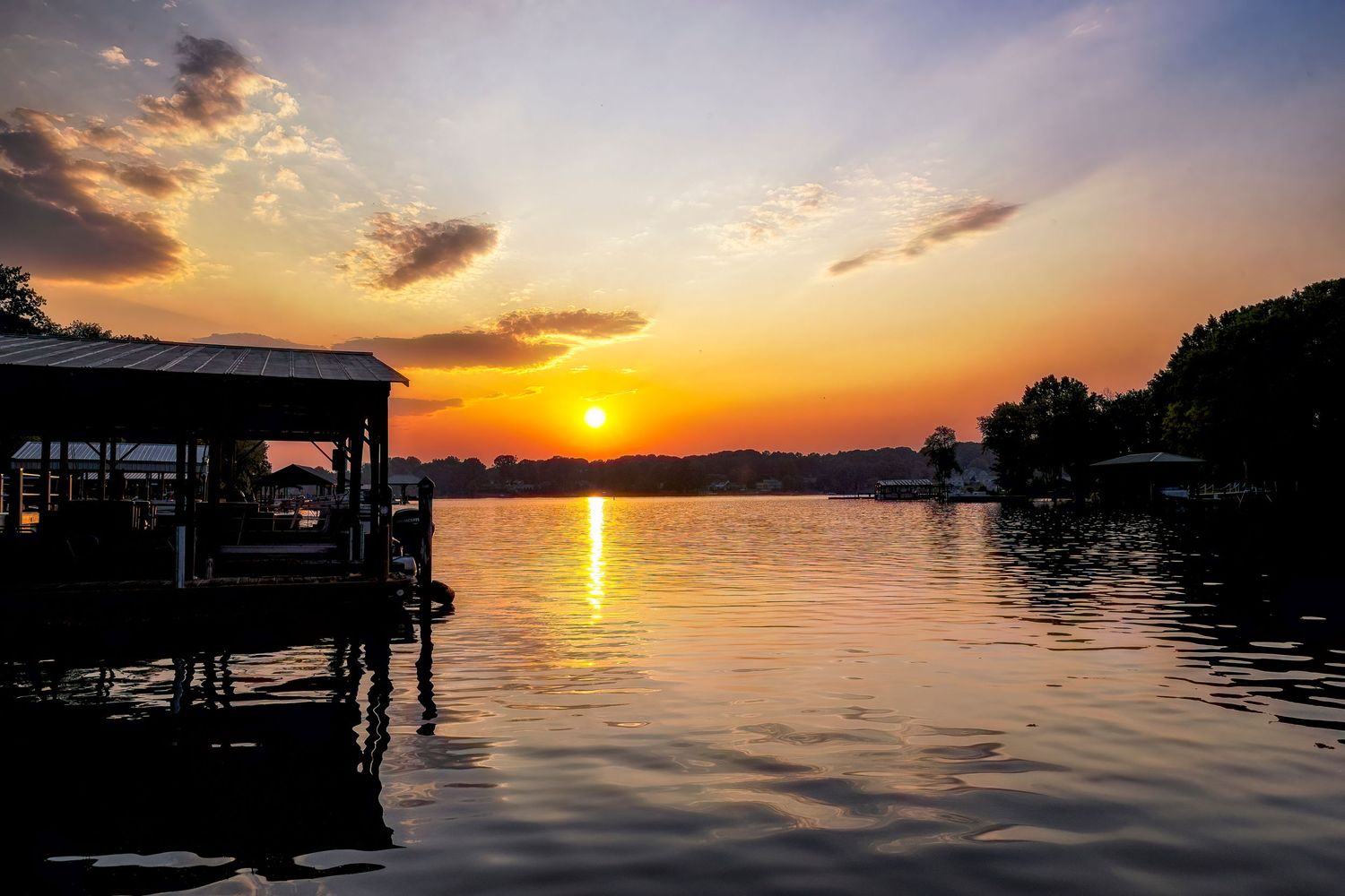 Stunning sunset views over a lake with silhouetted docks and golden reflections on calm waters.