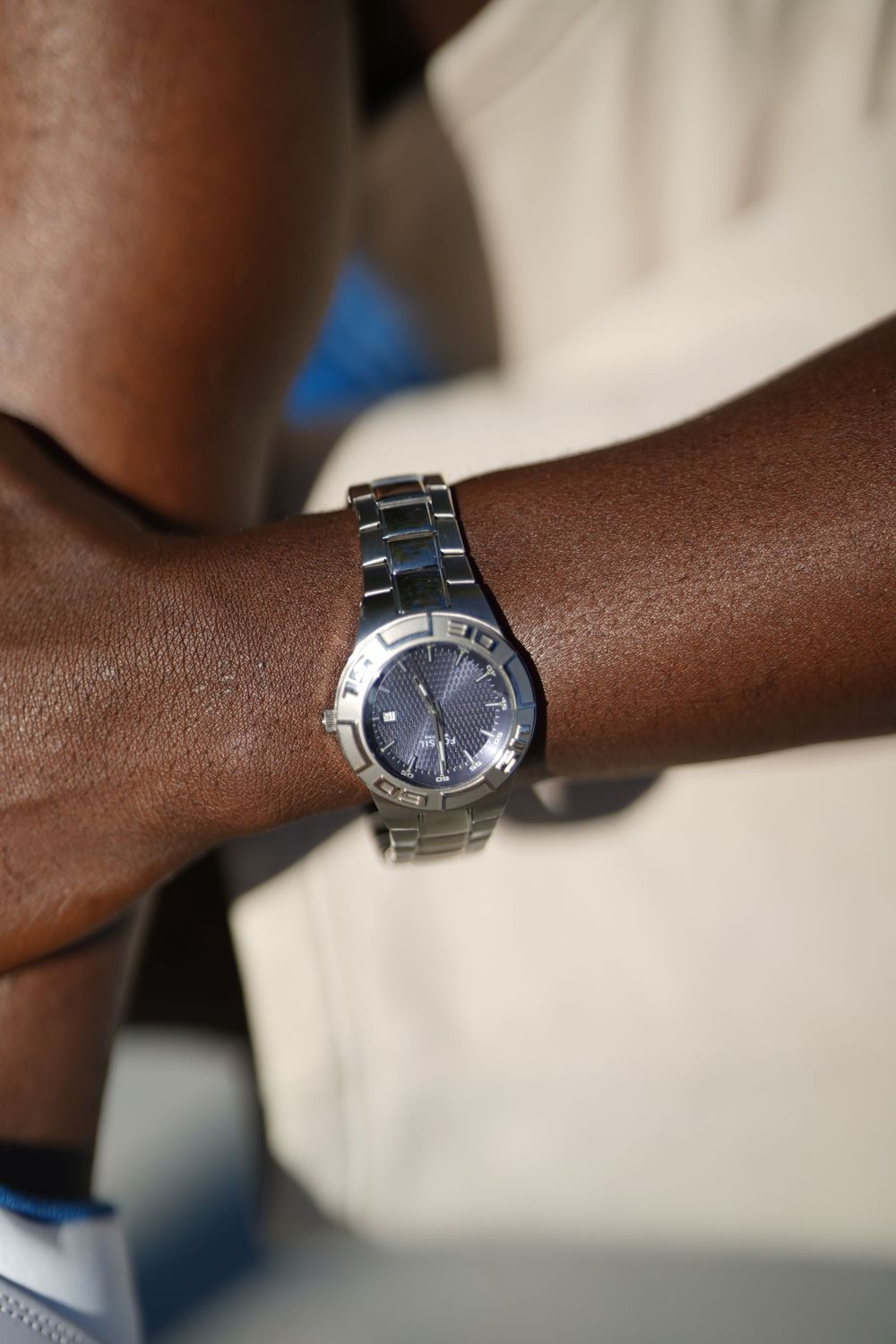 Close-up of silver watch on wrist showing metallic band and dark face.