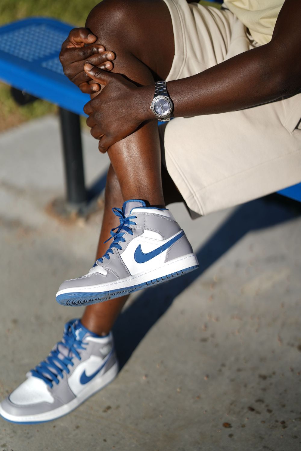 Person sitting on bench showing Nike sneakers and silver watch while relaxing.