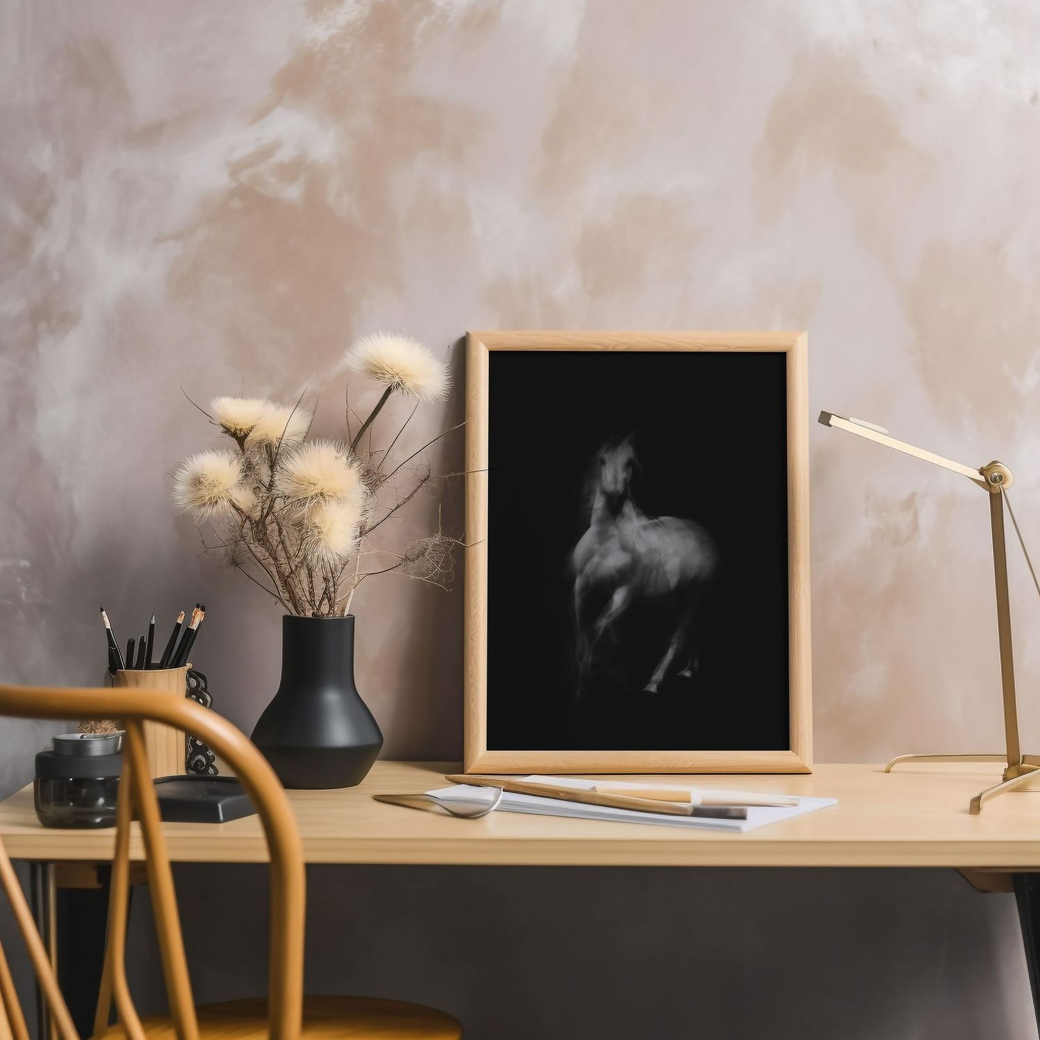 Minimalist desk setup with framed horse art print, dried flowers, and task lamp.