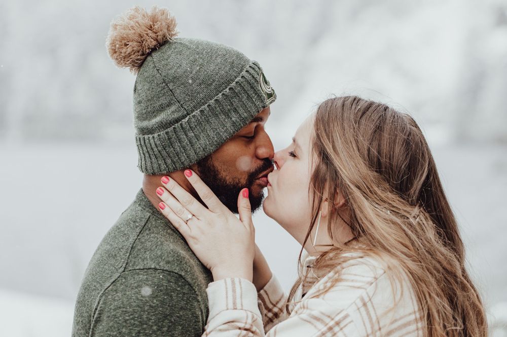 A couple kisses in the snow during an engagement session with Pamela Clark