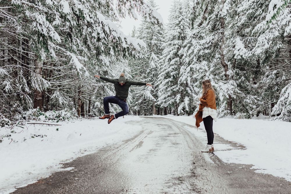 A man leaps in excitement as she said yes in the snow during an engagement session with Pamela Clark
