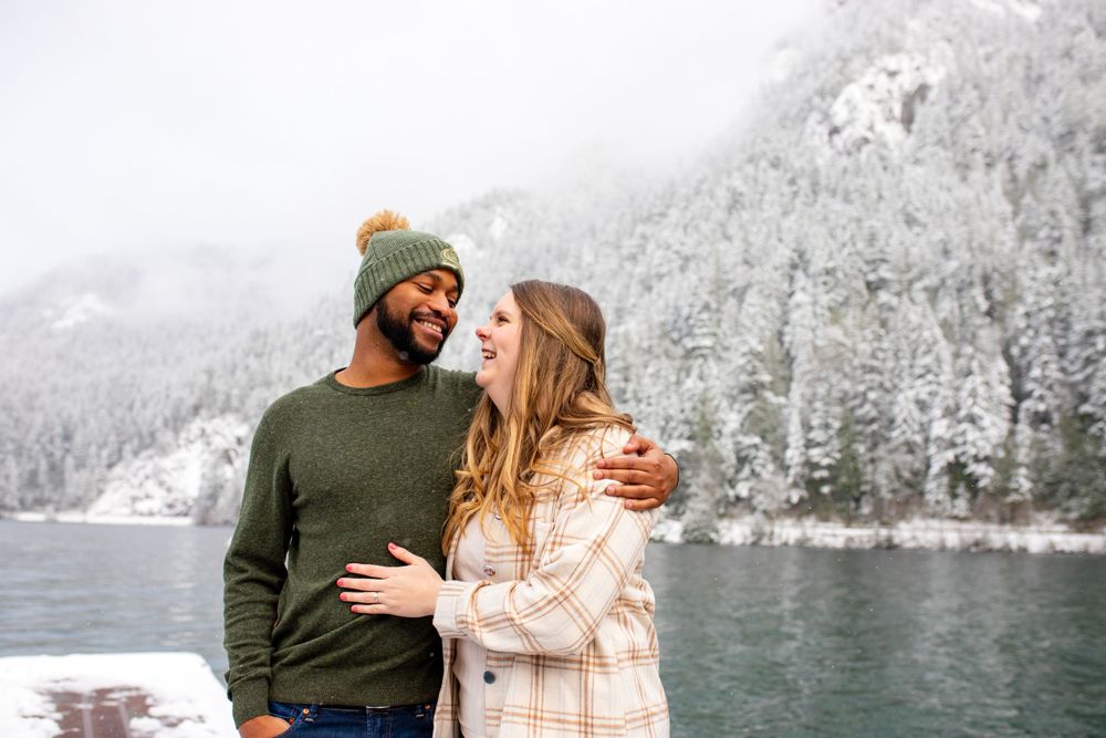A couple hugs while looking at each other in the snow during an engagement session with Pamela Clark