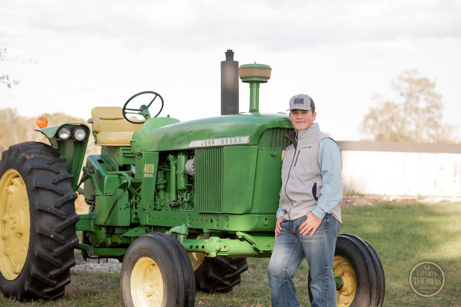 Classic green John Deere tractor displayed outdoors with person in casual clothing.