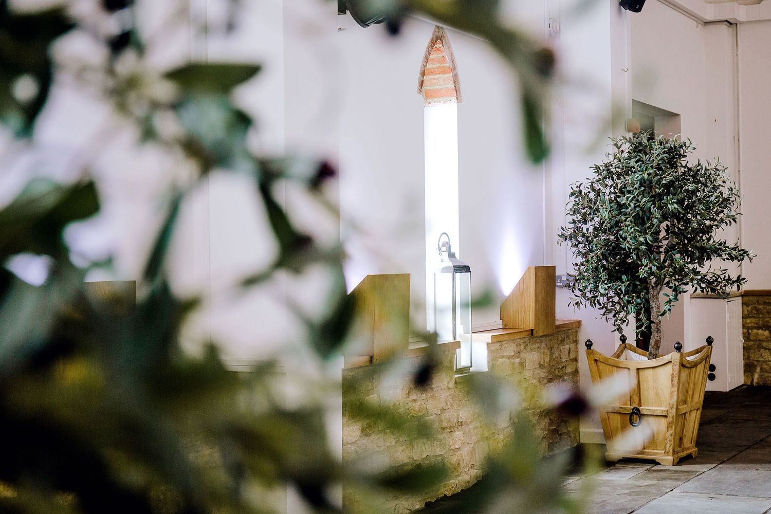 Interior church space with golden chairs and a potted tree visible through foliage.
