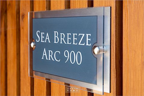 Modern sign reading 'Sea Breeze Arc 900' mounted on wooden paneling.