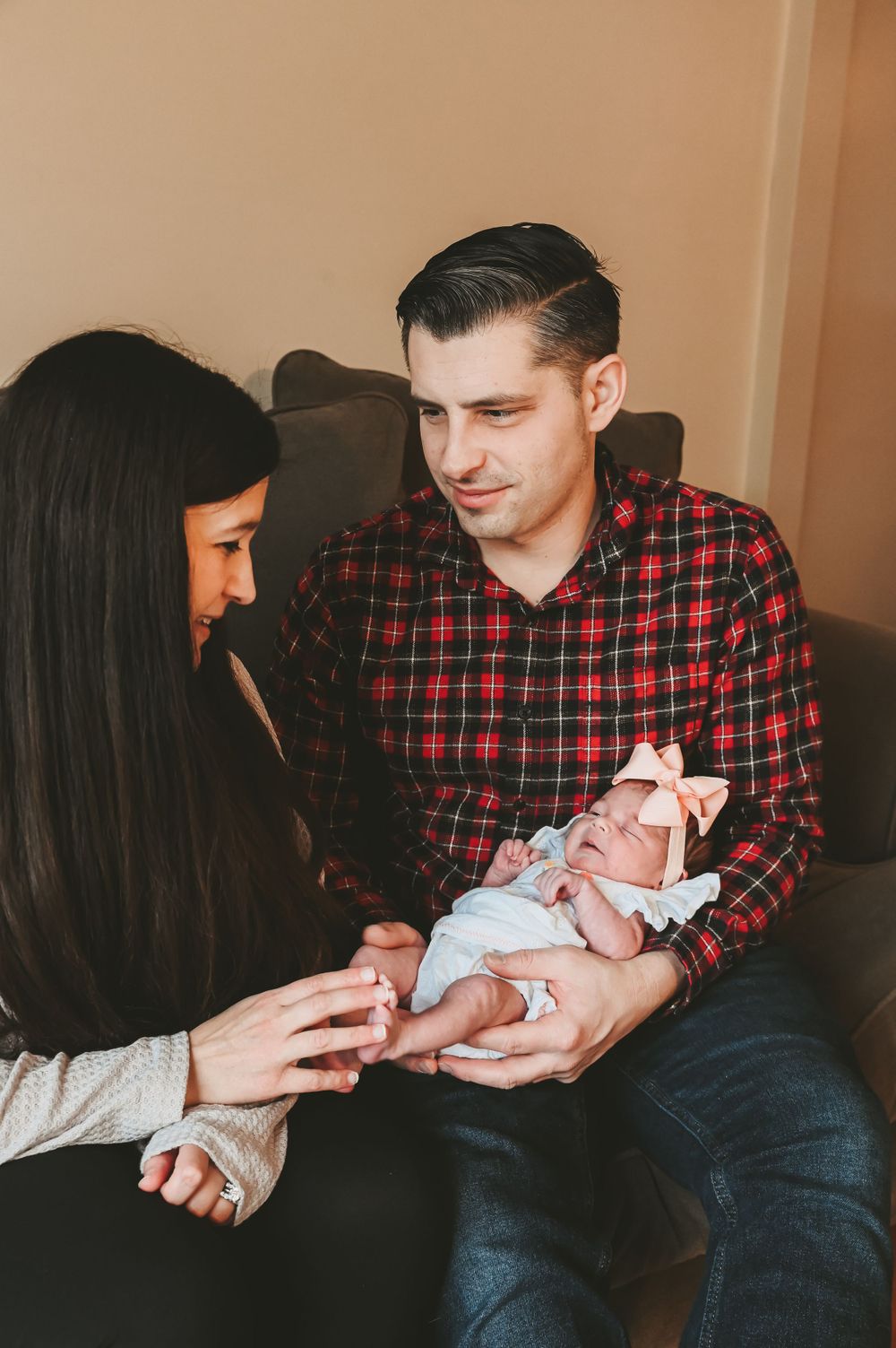 Intimate family moments as parents bond with their newborn baby on couch.