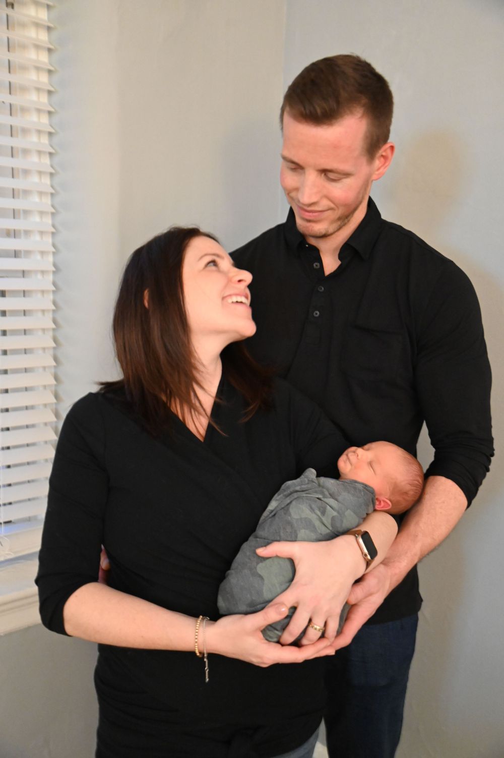 Parents in matching black shirts share joyful moments with their newborn baby.