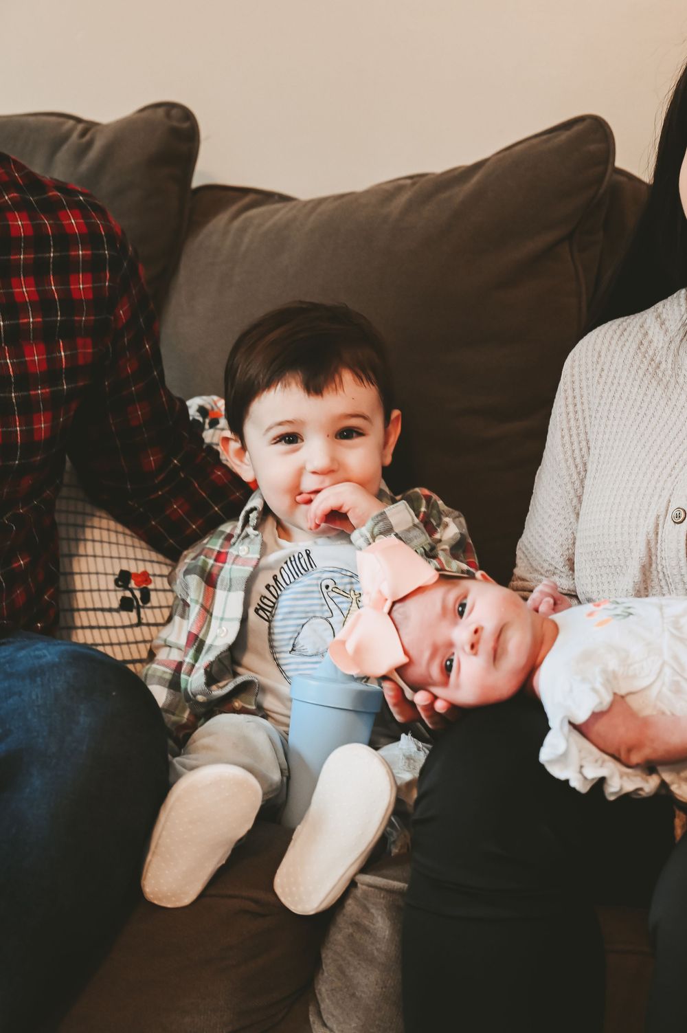 Family lounging together on brown couch sharing joyful moments with young child.