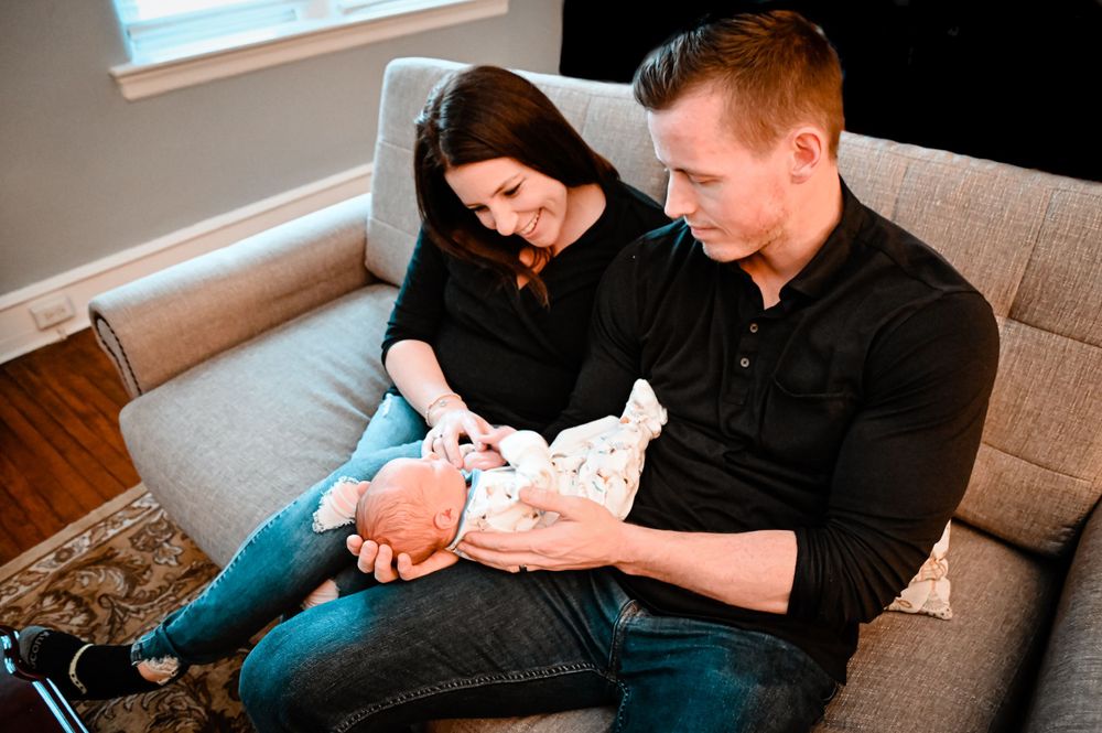 A tender moment captured in black and white as a person cradles a newborn baby on a couch.