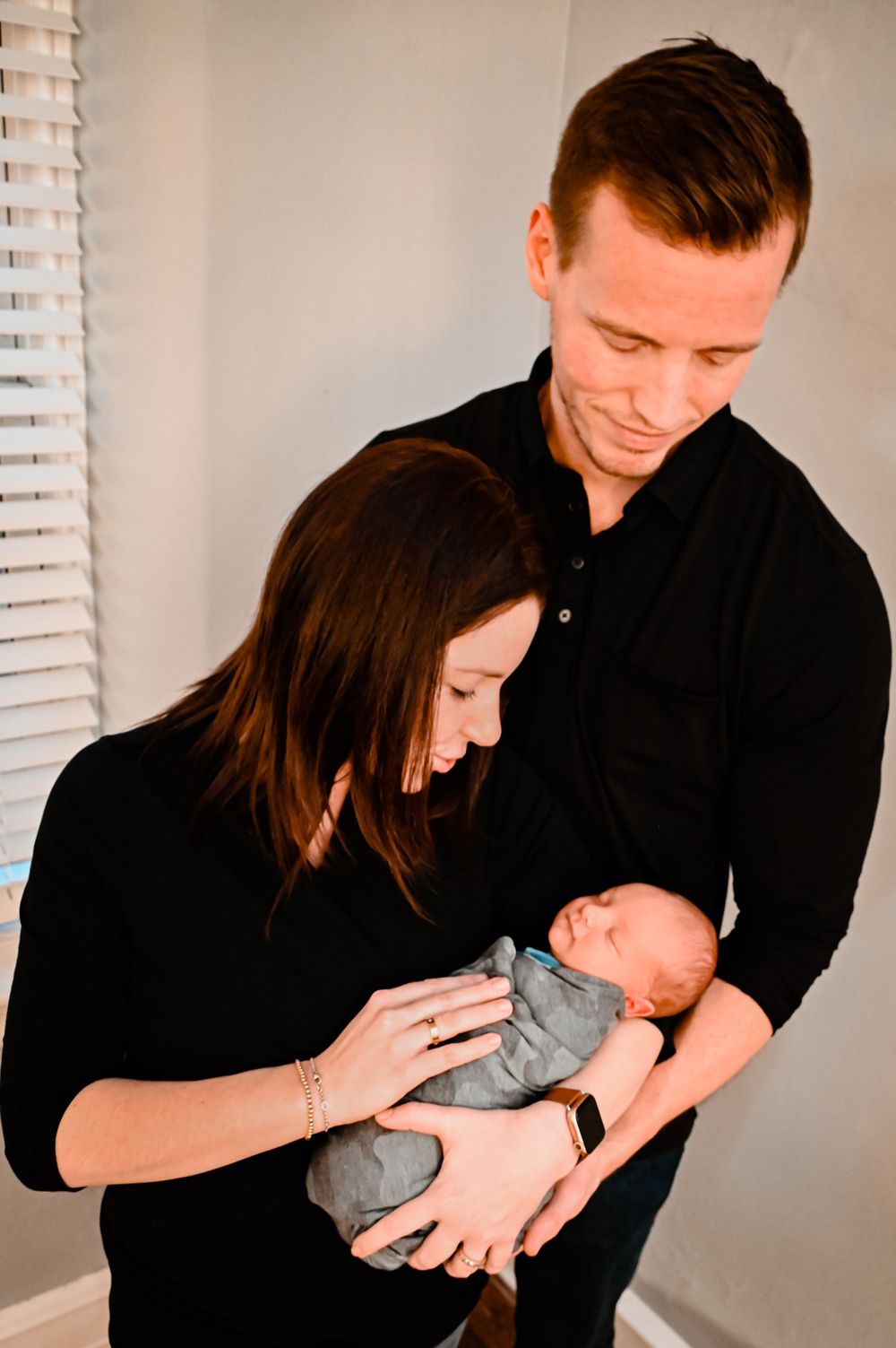 A series of tender moments as parents bond with their newborn in a sunlit room.