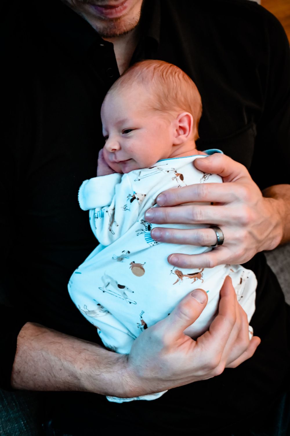 Intimate black and white photos of hands cradling a small baby in a light colored outfit.