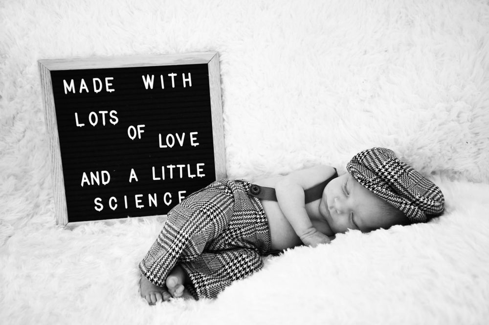 Newborn photo with letter board saying Made with Love and Science.