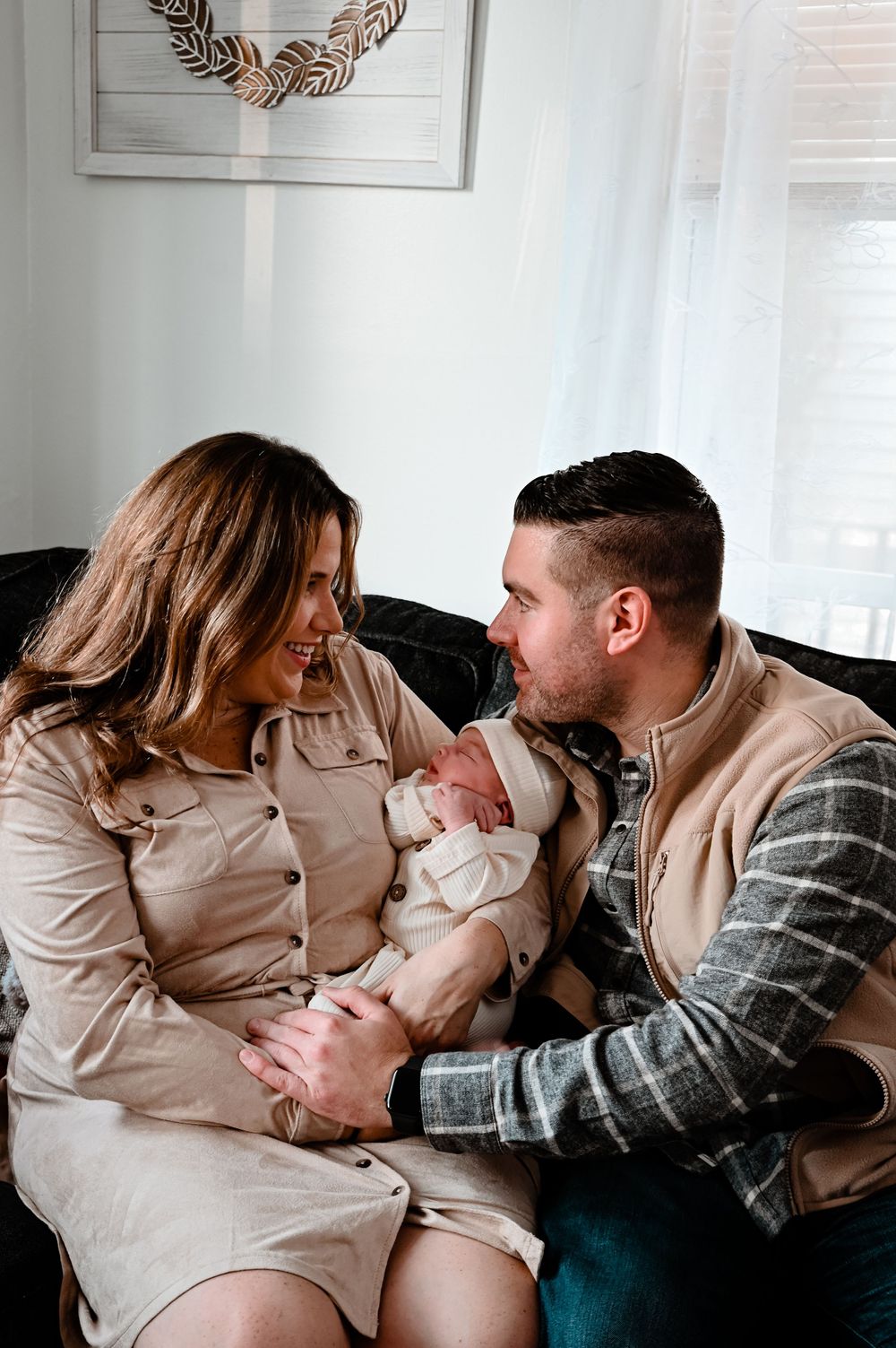 Parents sharing tender moments with their newborn baby on a couch.