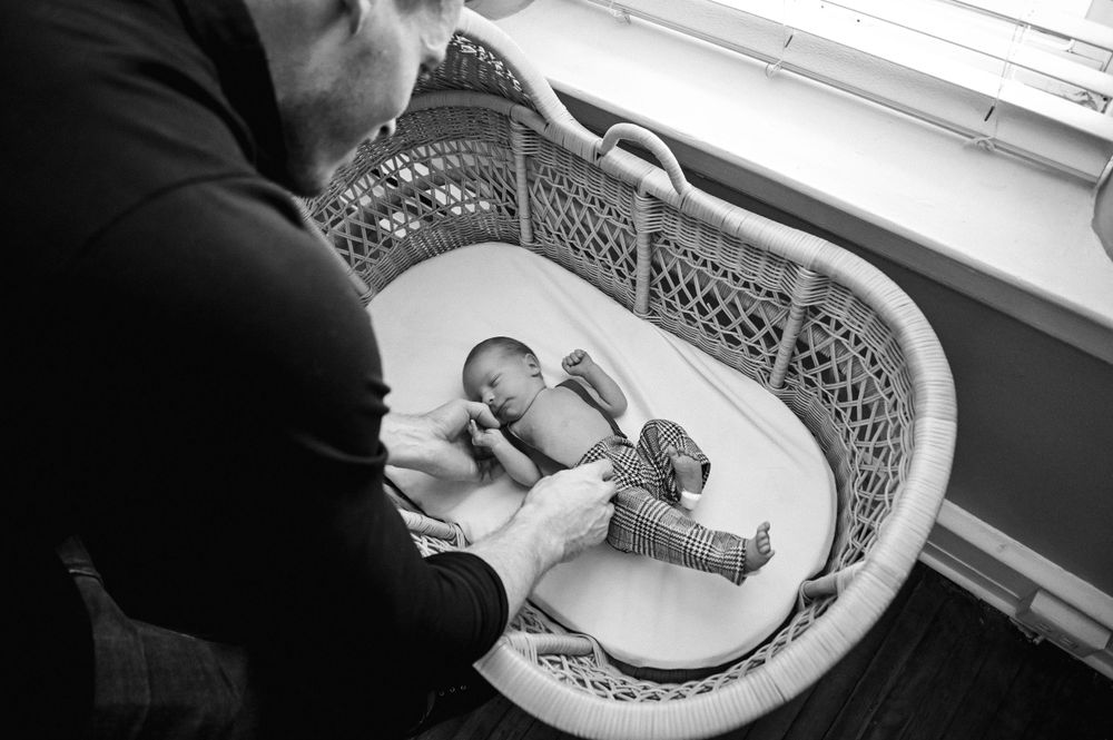 Newborn baby sleeping in ornate white bassinet.