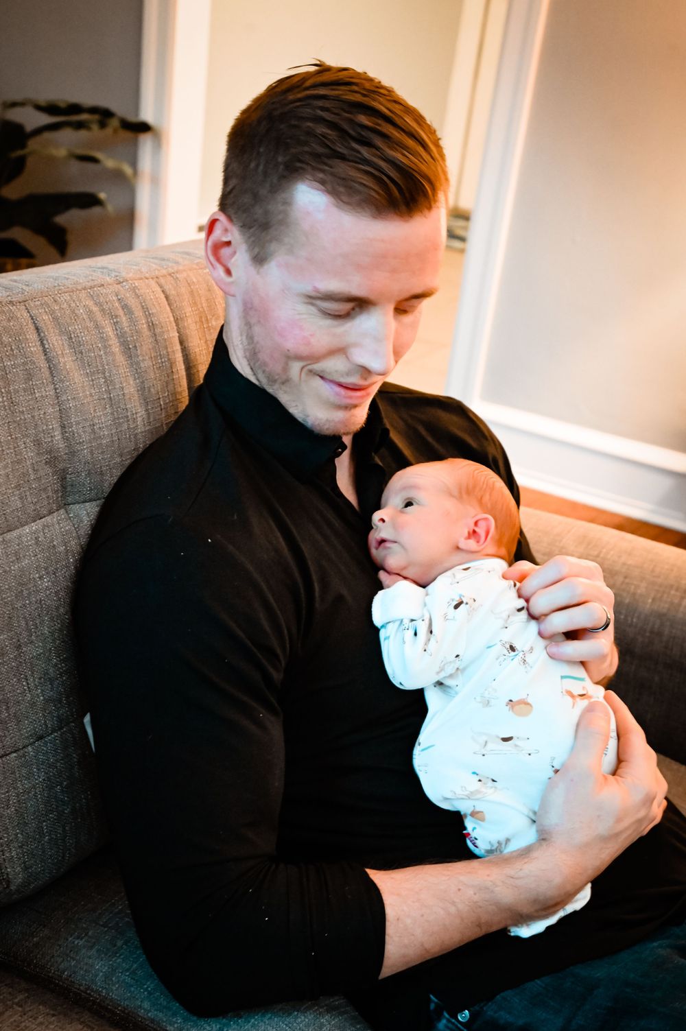 A person in a black shirt holds and gazes lovingly at a baby wearing a light colored onesie.