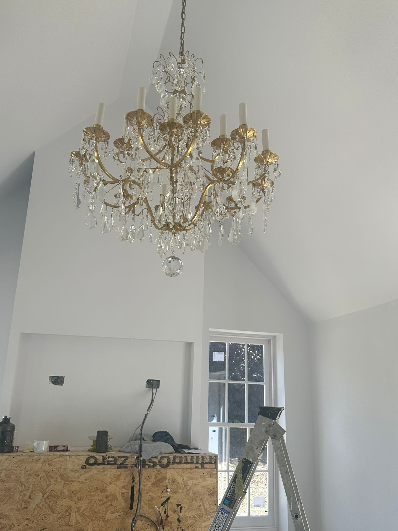 Crystal chandelier with gold accents hanging from vaulted ceiling in renovated space.