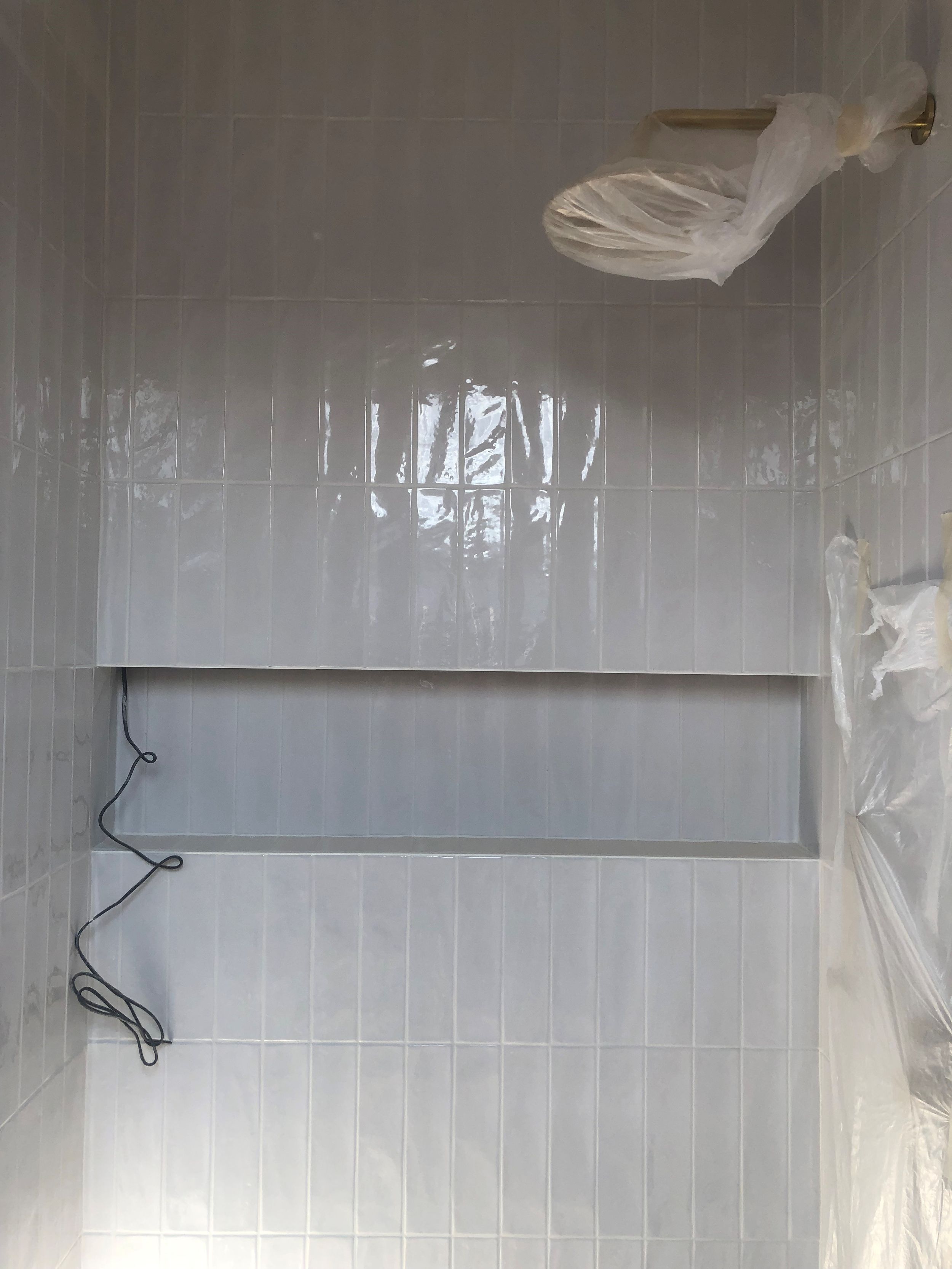 White tiled wall with electrical wiring installation during renovation.