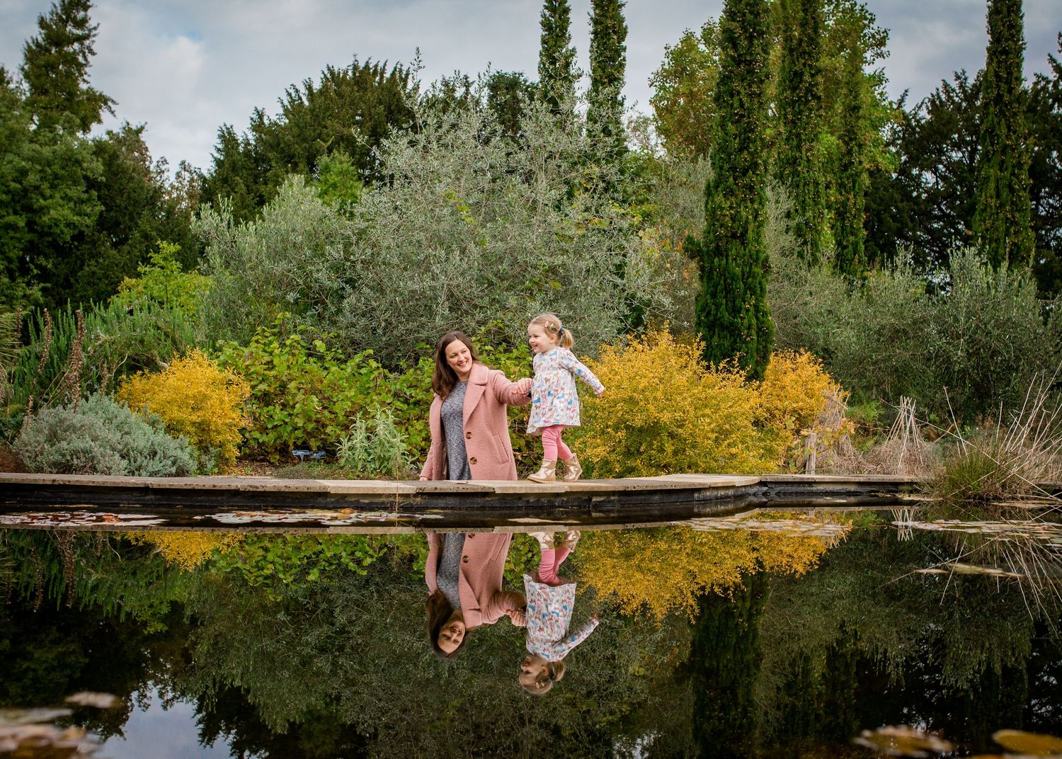 mother and child walking along the wall of a pond