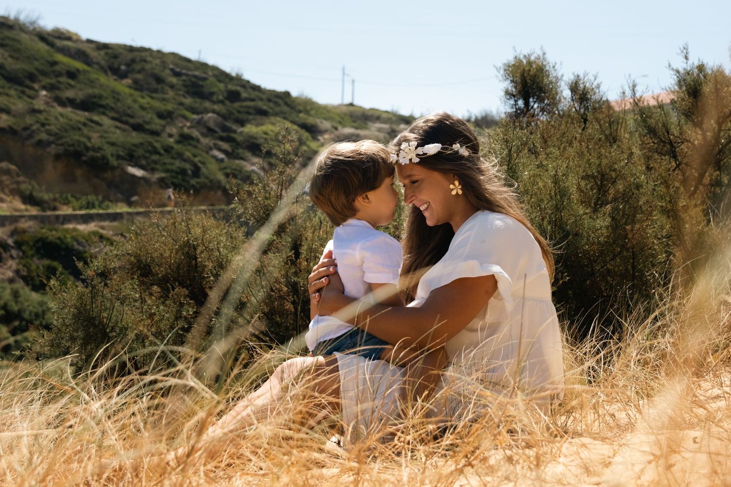 People spending time together in a sunny hillside with dry grass.