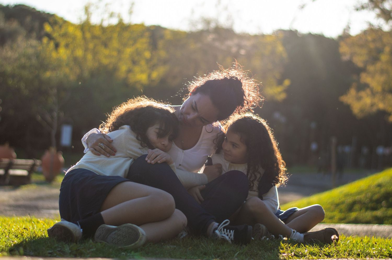 Friends lying together on grassy hill during sunset with beautiful lighting.