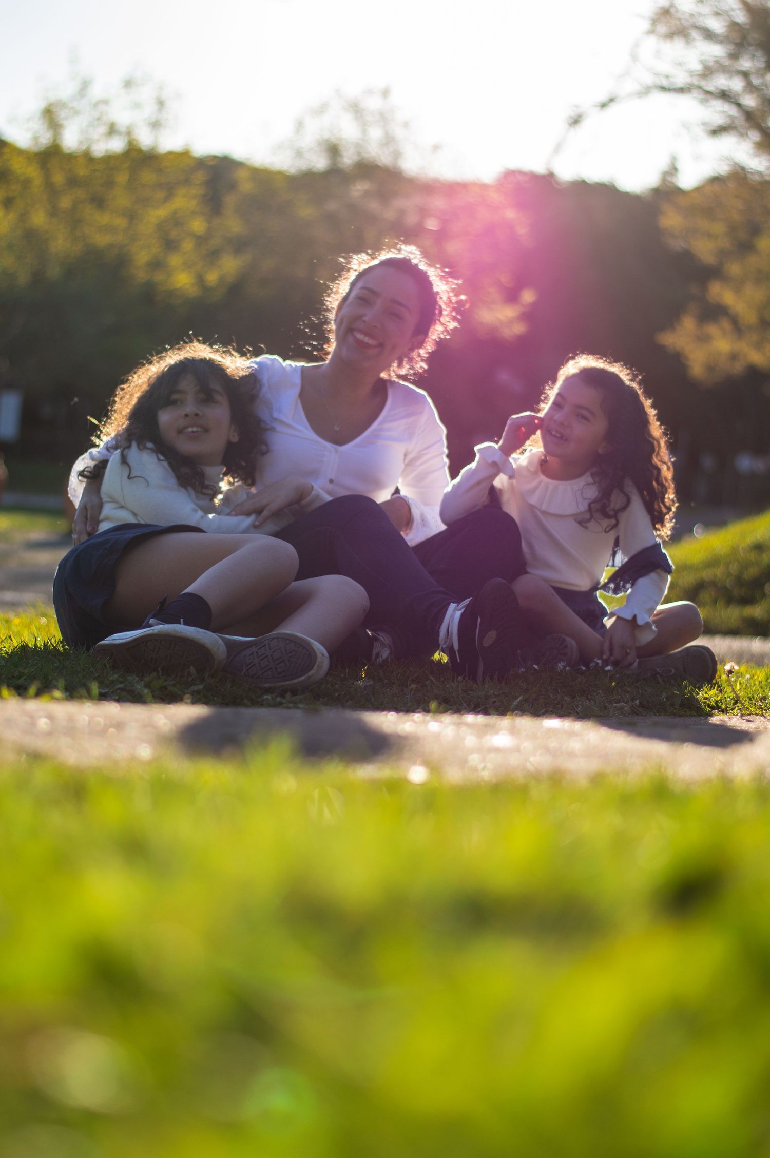 Group relaxing on grass during golden hour with sun flare effects.