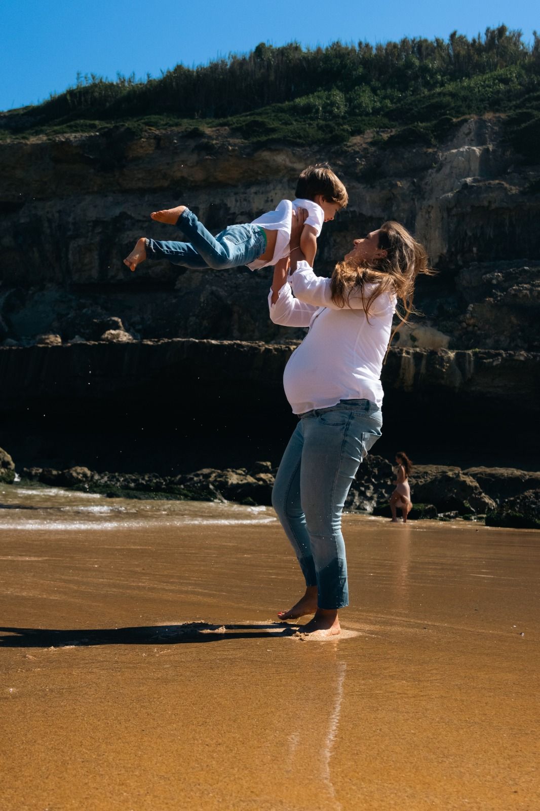 People playing and having fun on a sandy beach with cliffs in the background.