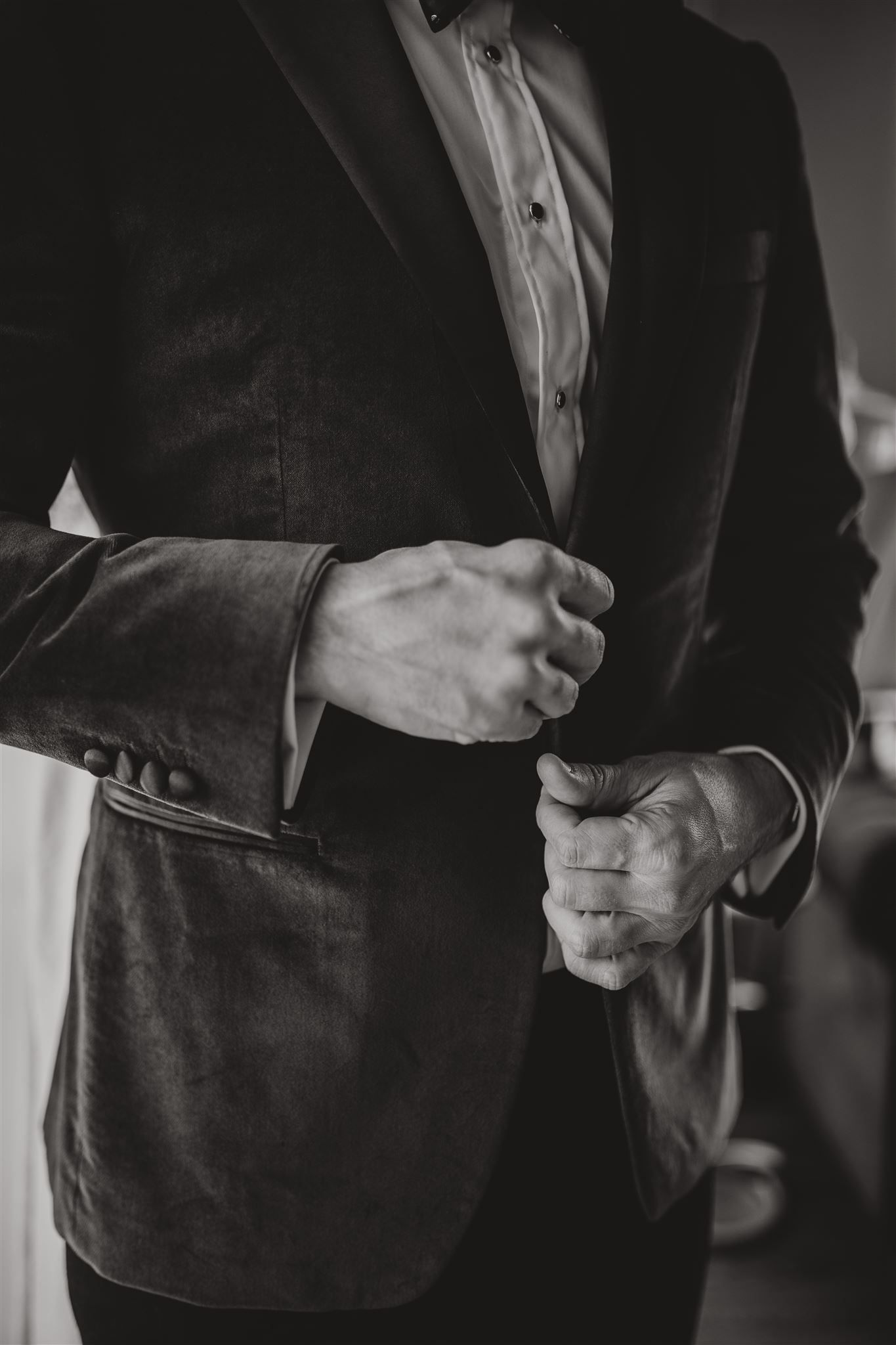 Close-up of hands adjusting formal black suit jacket.