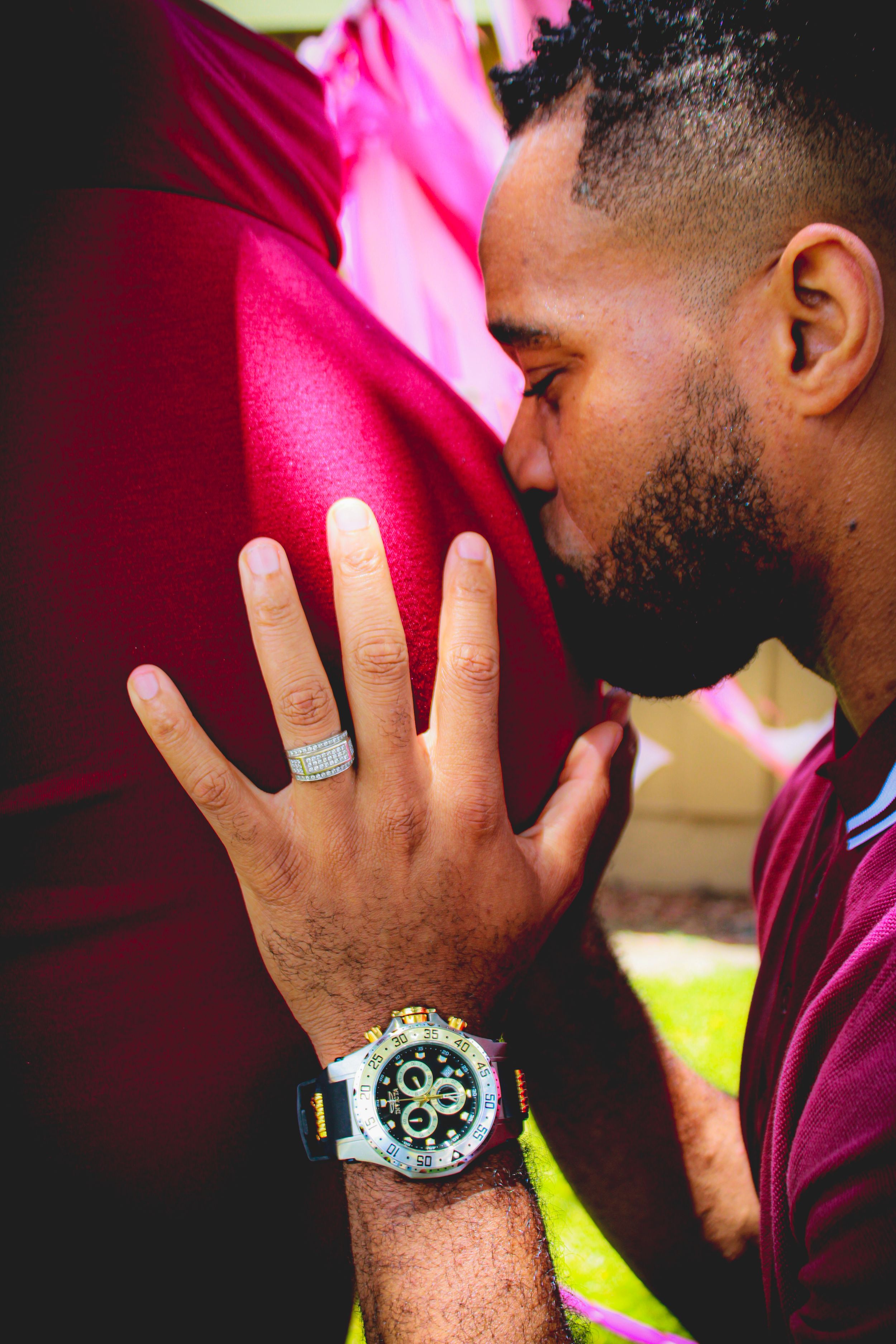 Close-up of hand wearing silver ring and stylish watch against red background.