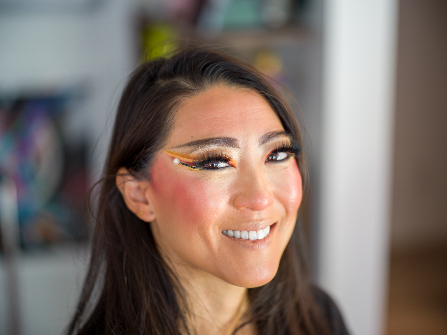 Glamorous makeup look featuring dramatic eyeliner and rosy blush.