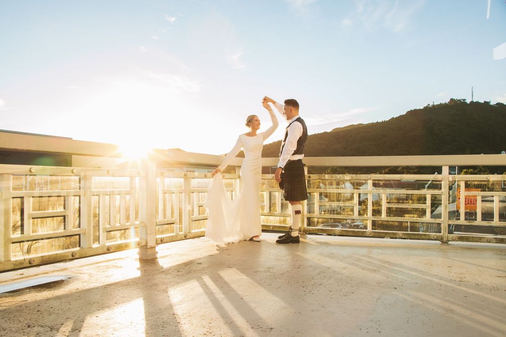 A couple shares a romantic moment on a wooden deck at sunset with mountains in the background.