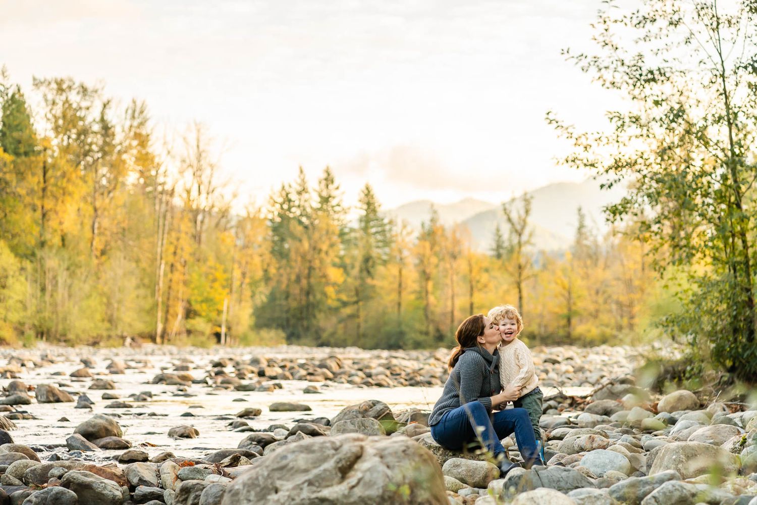 Mother kissing sons cheek by the river in North Bend.