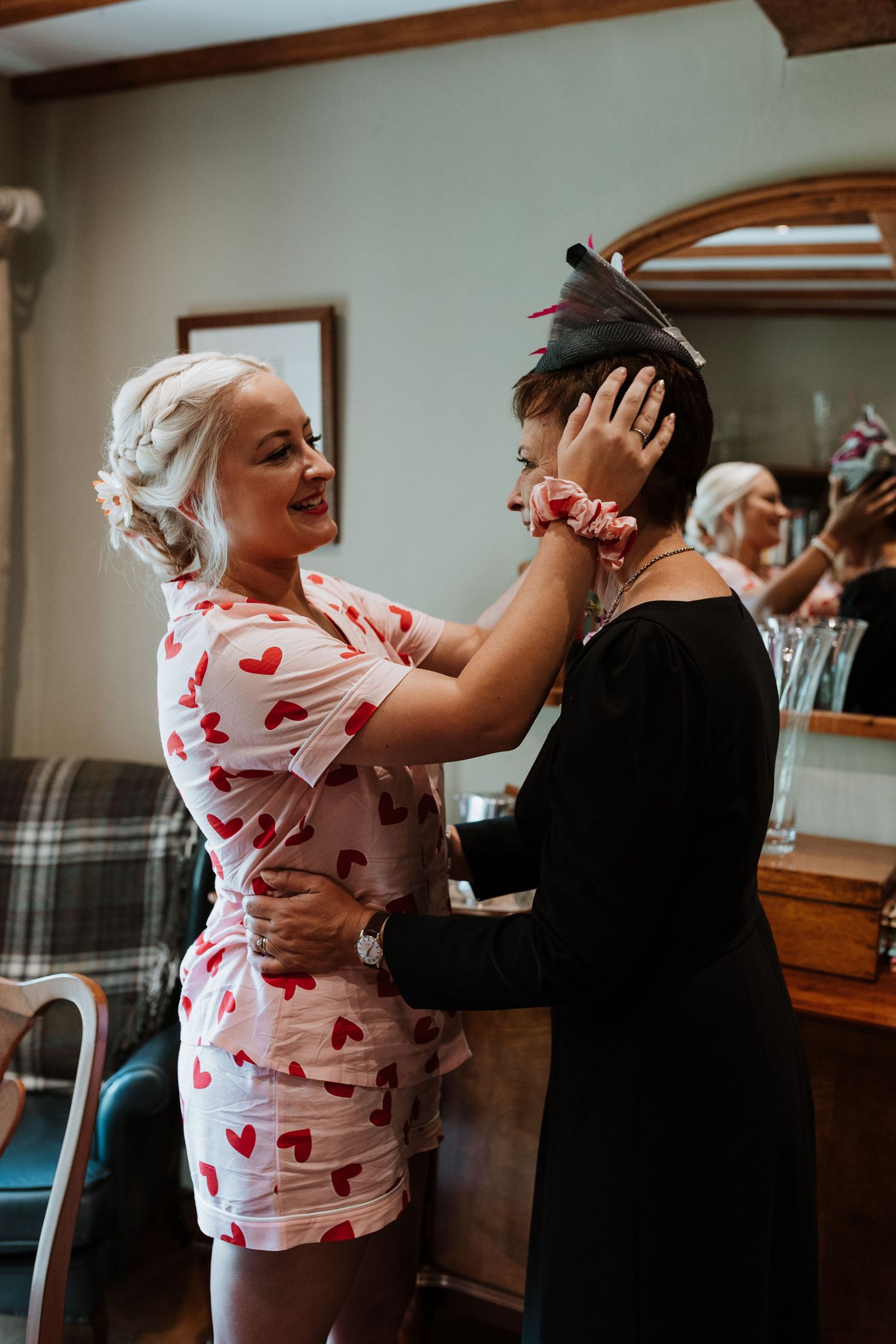 bride helping her mother put on her hand made hat the bride made for her mum