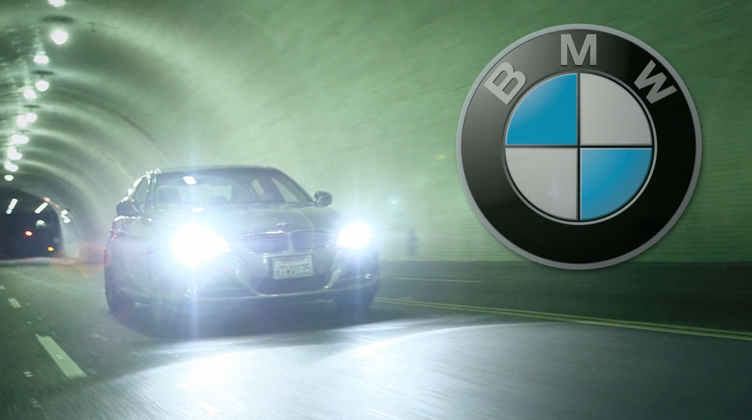 BMW logo displayed with car headlights glowing in a green-lit tunnel.