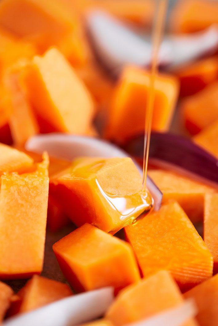 Fresh cantaloupe cubes being drizzled with honey in bright lighting.