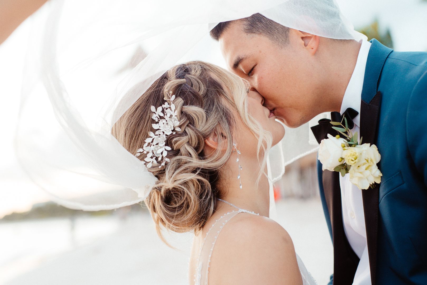 Elegant wedding couple sharing a tender moment against a bright background.