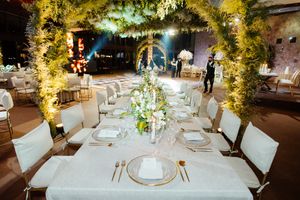Elegant wedding reception tables decorated with white linens and floral centerpieces under warm lighting.