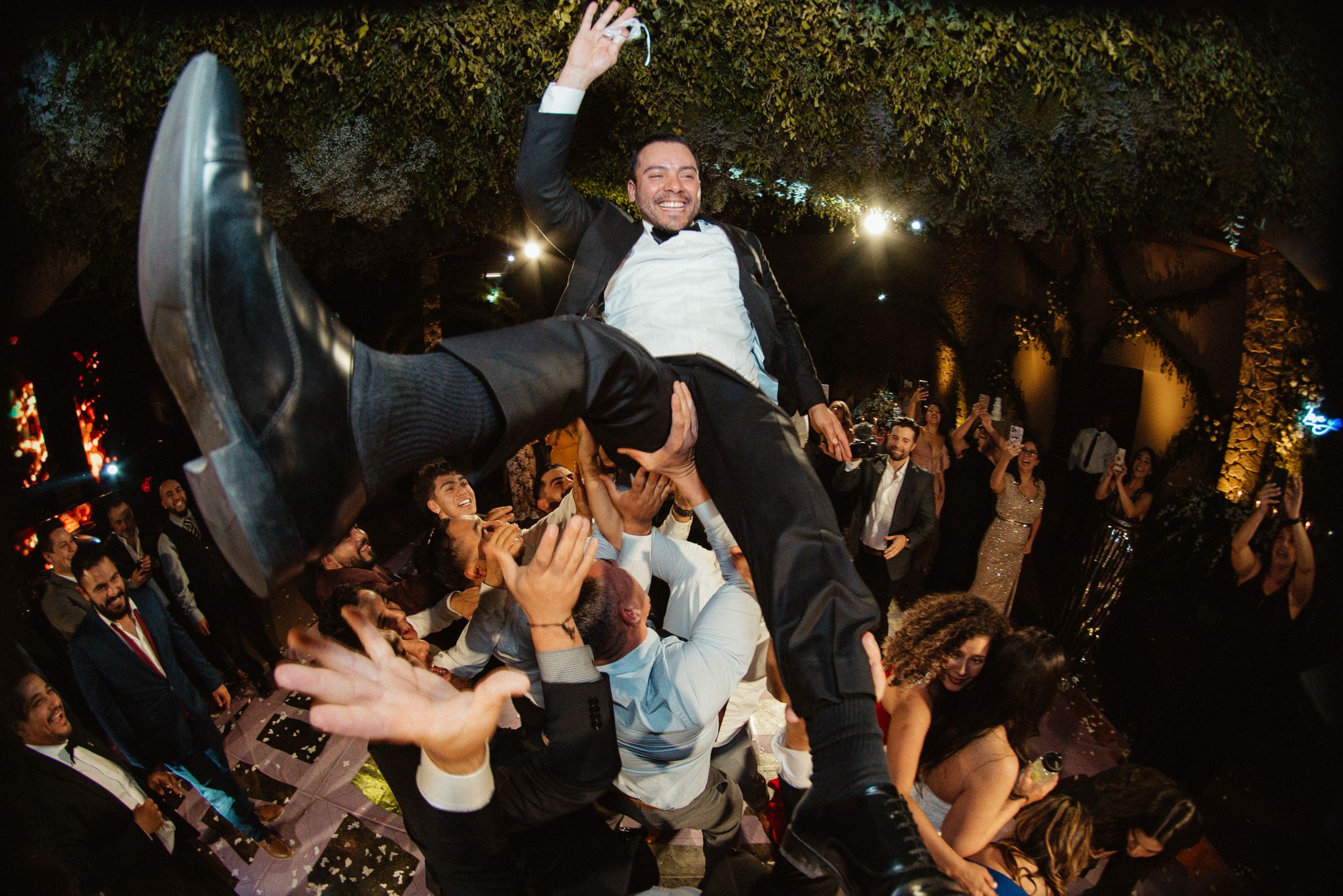 Wedding celebration with dancing guests under evening lights.