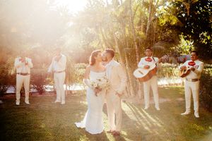 Wedding party celebration in outdoor garden setting with natural sunlight filtering through.