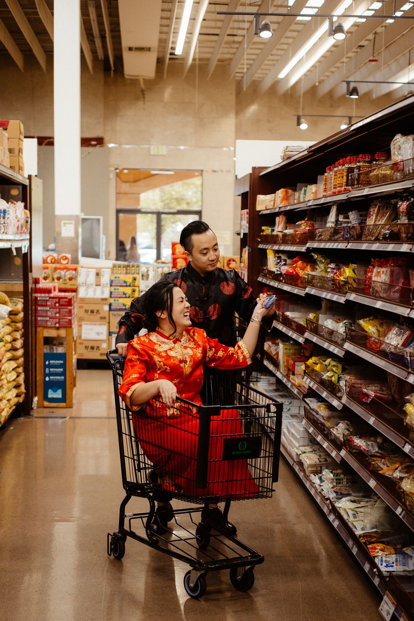 Couple in traditional red attire shopping in grocery store aisle.